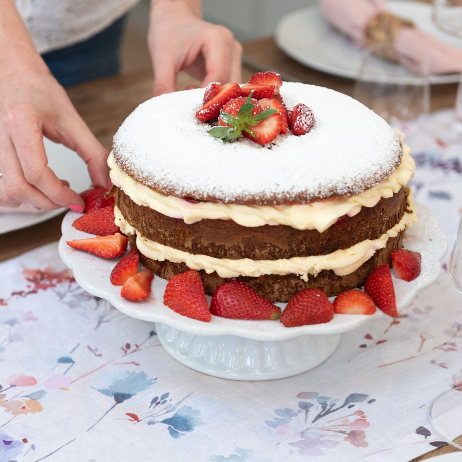 white cake stand with victoria sponge and strawberries